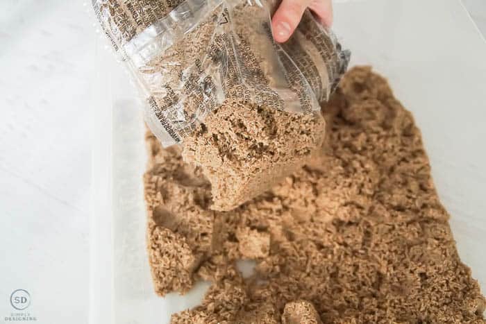 pour kinetic sand into bin for sensory play