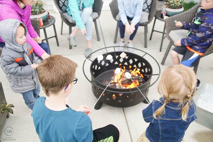 roasting marshmallows over fire pit - summer dinner party idea