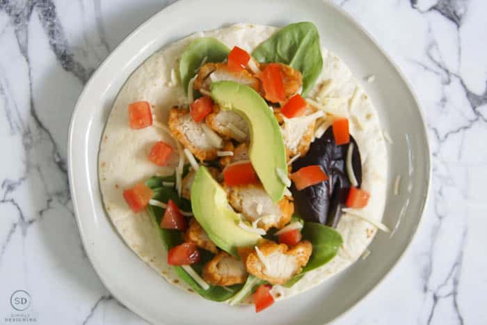 tortilla with lettuce and chicken and cheese and avocado and tomato