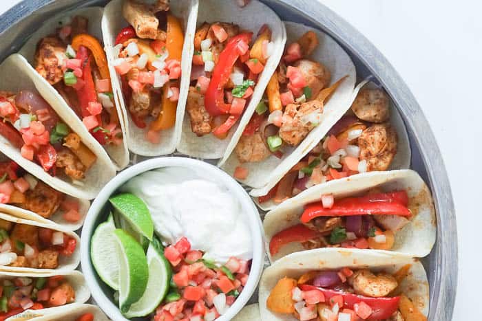 one pan chicken fajitas with toppings of sour cream pico and lime