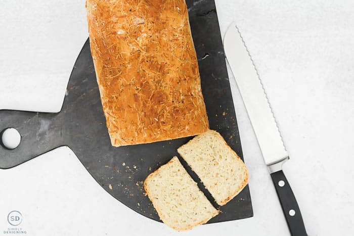 this herb artisan bread is so simple to make - sliced and cut bread on black marble cutting board
