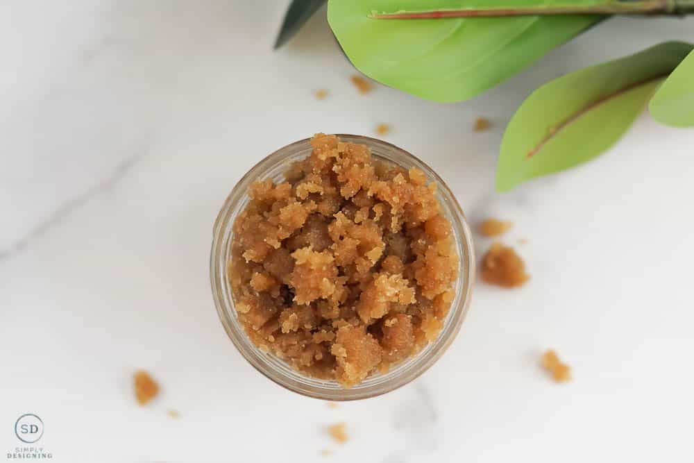 looking down on sugar scrub made with brown sugar and green leaves in the top left corner