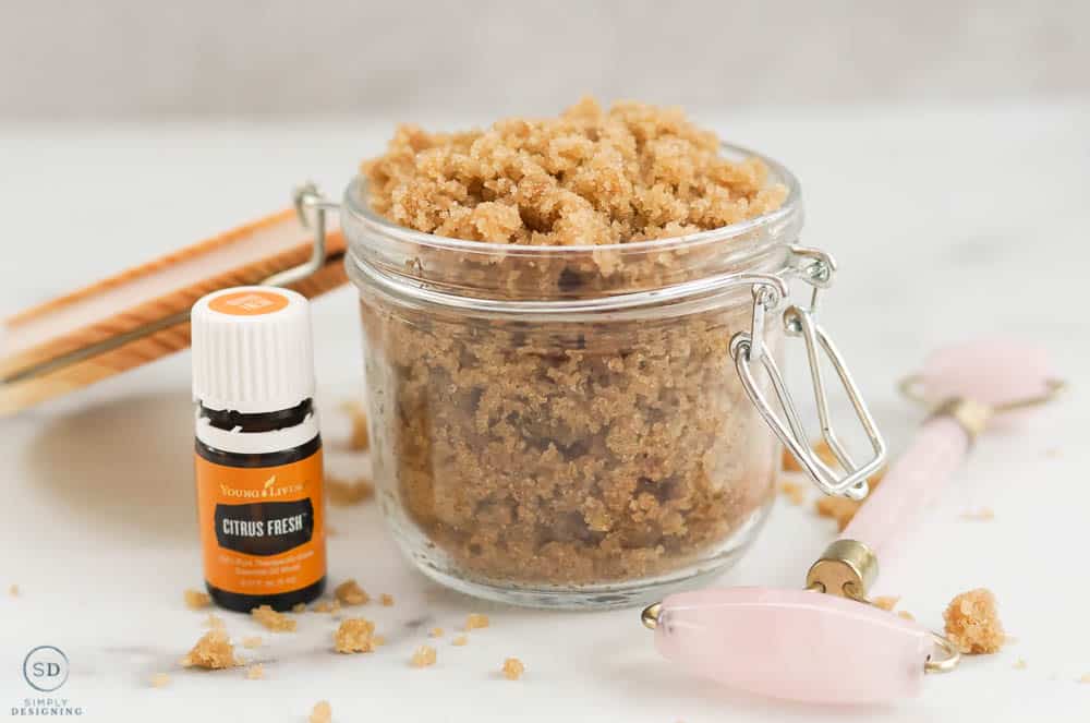 Citrus Brown Sugar Face Scrub in a glass container with citrus fresh essential oil and a rose quartz face roller