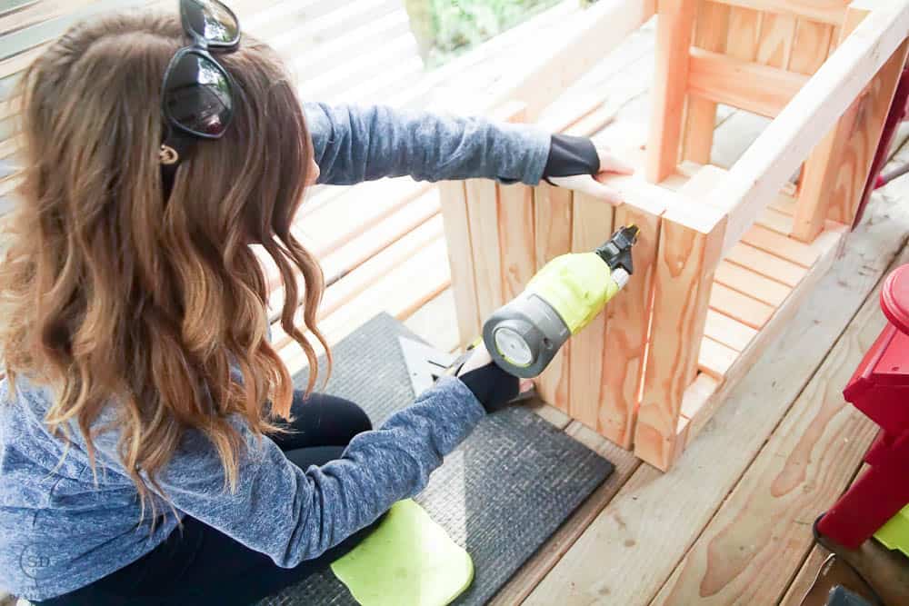 using nail gun to attach siding boards to pet house
