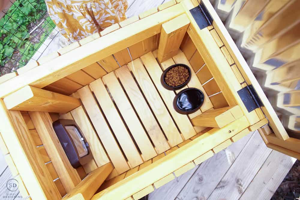looking inside the DIY cat house with black bowls of food and water in the bottom