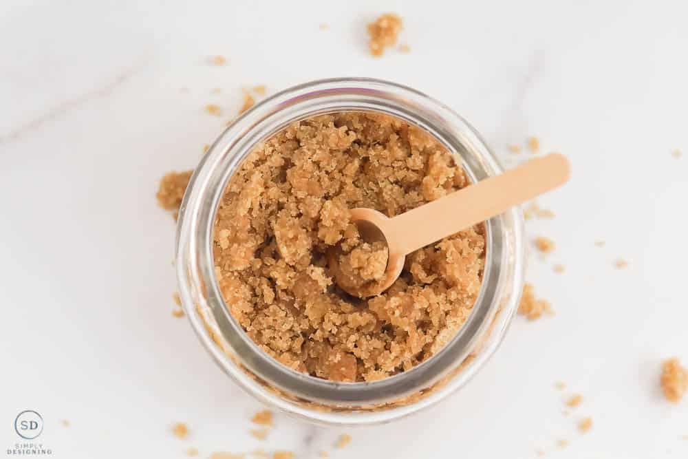looking down on brown sugar hand scrub with wooden spoon in glass jar horizontal photo