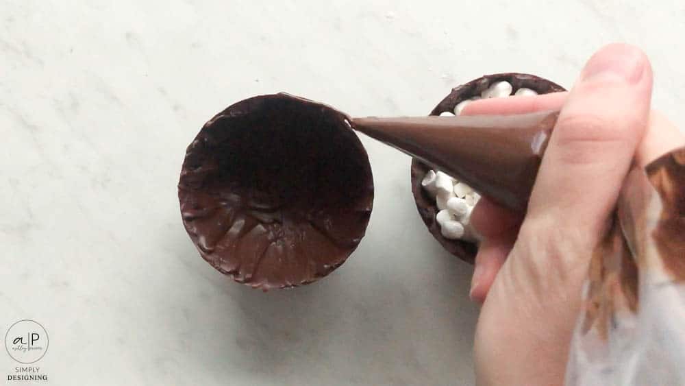use a decorating bag to add chocolate and attach sphere halves together