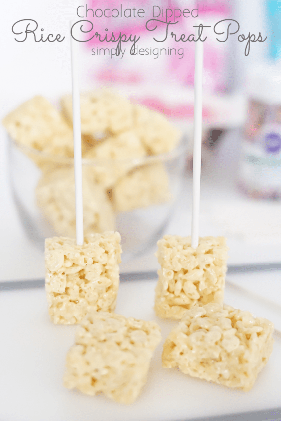Rice Crispy treats that were cut in half with a sucker stick placed in them standing up on the cutting board