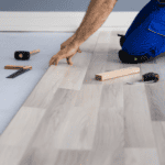 image of guy in jeans installing lvp or laminate flooring - LVP vs LAMINATE FLOORING